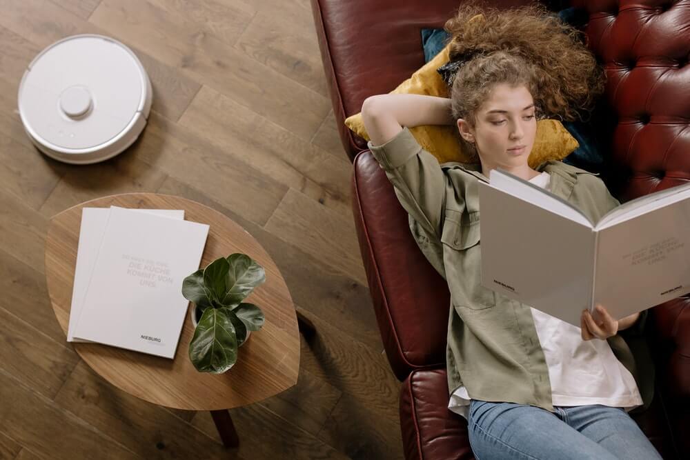 woman reading book on leather couch